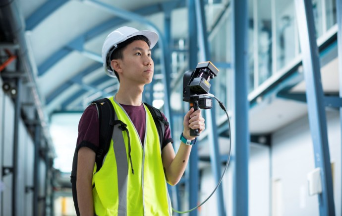 Researcher using a handheld 3D laser scanner in a structural engineering environment